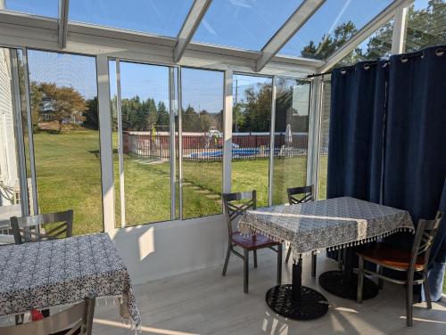 a screened porch with tables and chairs and windows at The Parrsboro Mansion Inn in Parrsboro