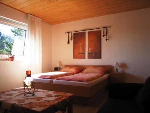 a bedroom with two beds and a window and a table at Haus Witten Höhen in Cuxhaven