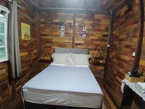 a bedroom with a bed in a room with wooden walls at Casa de campo rústica 21km vila germânica Bnu in Blumenau