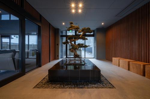 a bonsai tree in the middle of a room at ELSUENITOhinase in Hinase