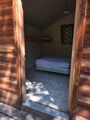 a door to a room with a bed in it at Sleeping Cabin East, roughing it gently in Verdure