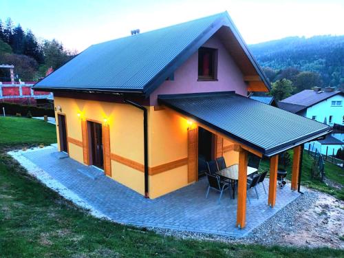 a small house with a black roof and a table at Cicha Chata Szczyrk in Szczyrk