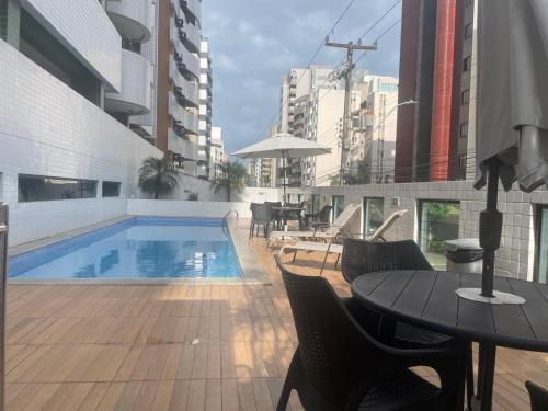 a patio with a pool and a table and chairs at Apt 02 quartos em Ponta Verde in Maceió