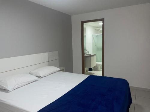 a bedroom with a white bed with a blue blanket at Apt 02 quartos em Ponta Verde in Maceió