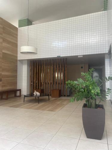 a lobby with a potted plant in the middle of it at Apt 02 quartos em Ponta Verde in Maceió