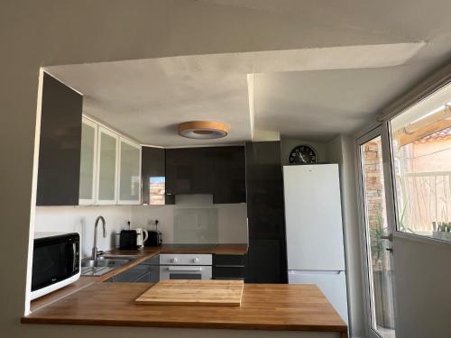 a kitchen with black cabinets and a white refrigerator at Hypercenter lovely duplex with Terrace CLIM WIFI in Aix-en-Provence