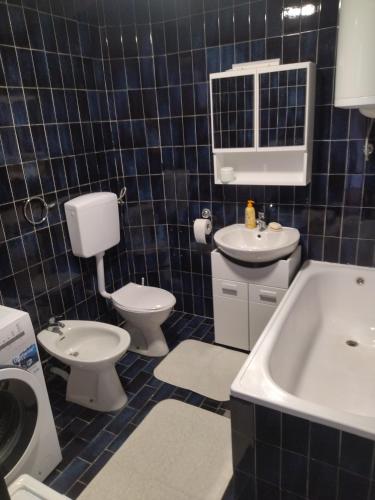 a blue tiled bathroom with a toilet and a sink at Andjela&Sara in Trebinje