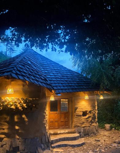 una pequeña casa de piedra con una gran puerta de madera en Janki's Commune - An Earthen Stay Amidst Old Manali, en Manali