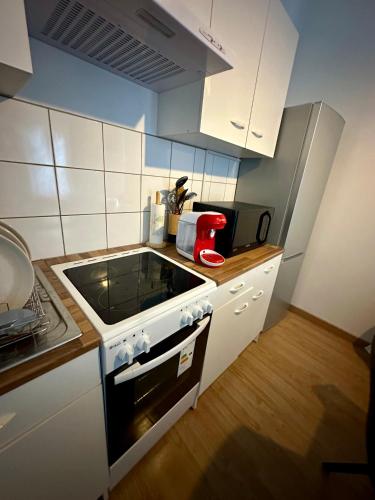 une cuisine avec des armoires blanches et un four à plaques de cuisson dans l'établissement Etoile, à Ault