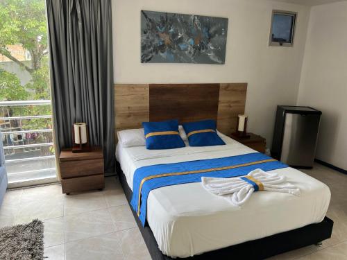 a bedroom with a large bed with blue pillows at Hotel Boutique Santa Ana in Cartago