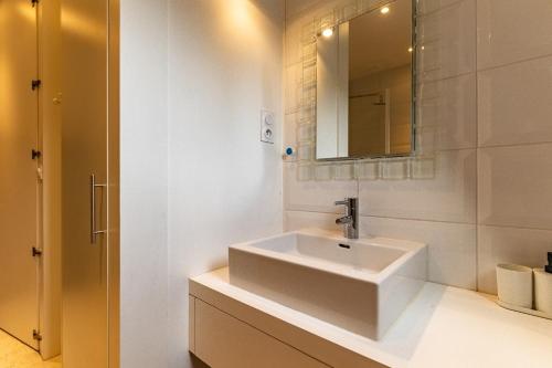 une salle de bain blanche avec un lavabo et un miroir dans l'établissement Appart Cosy 6 Personnes - Parking Gratuit - Centre Ville Historique Dijon, à Dijon