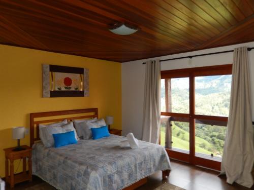 a bedroom with a bed and a large window at Pousada do Sonho, PARTE ALTA in Visconde De Maua