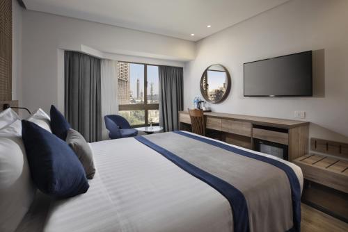 a hotel room with a bed and a flat screen tv at Pyramisa Suites Hotel Cairo in Cairo