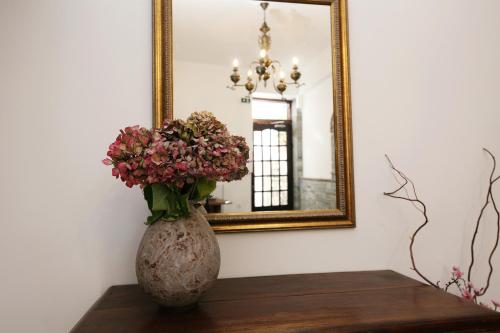 a vase with flowers on a table in front of a mirror at Marousos Central Guesthouse in Portariá