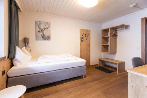 a small bedroom with a bed and a desk at Hotel Pinzgauerhof - Inclusive Evening Dinner in Saalbach Hinterglemm