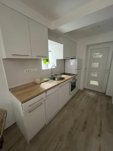 a small kitchen with white cabinets and a sink at Kolos Apartman 26 in Užice
