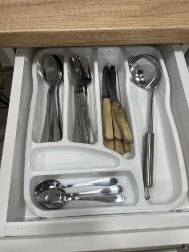 a white sink with utensils in a drawer at Kolos Apartman 26 in Užice
