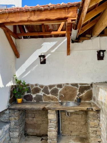 a stone counter with a sink under a roof at Къща за гости Куклите Петревене in Petrevene