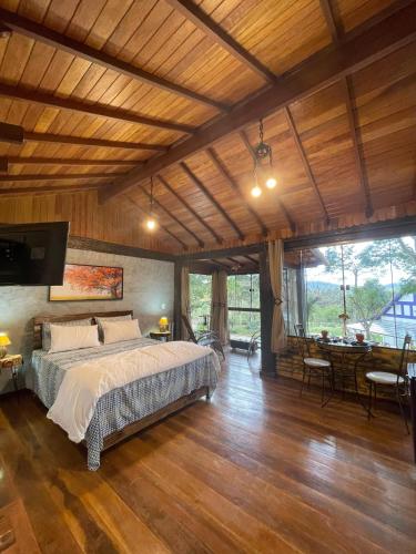a bedroom with a large bed and a dining room at Cabana Zen - Sítio Gaia Magia in Miguel Pereira