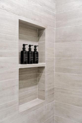 a bathroom with three black bottles on a shelf at Secluded Luxury Mansion with Sleek, Modern Design, High-End Amenities, and Spectacular Views in Carpintero