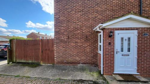 a brick building with a blue door and a fence at Nest & Rest En-Suite in Ashford
