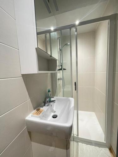 une salle de bain blanche avec un lavabo et une douche dans l'établissement Appartement proche de l'hôpital, à Tulle