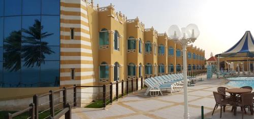 a resort with a pool and chairs and a building at Tio Sea Resort in Al Khor