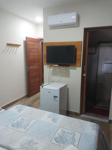 a room with a bed and a tv on the wall at Pousada Tia Rosa in Parnamirim