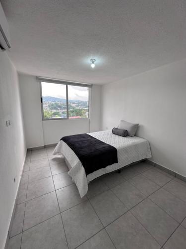 a bedroom with a bed in a white room with a window at View 15, San Francisco Tower in San Salvador
