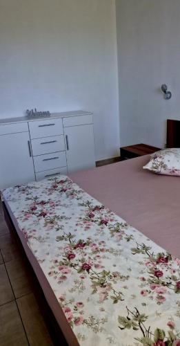 a bed with a flowered blanket on top of it at Luxus Apartments in Kelibia