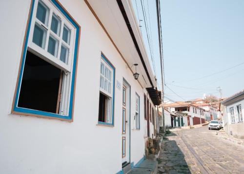 a white building with blue windows on a street at Hospedagem Rancho Fundo in Diamantina