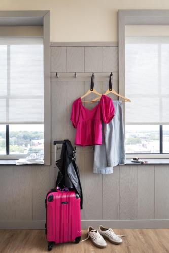 a pink shirt and a pink suitcase in a room at Moxy Springfield Downtown in Springfield