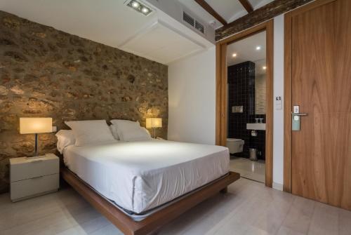 a bedroom with a large bed and a stone wall at Hotel Nou Romà in Denia