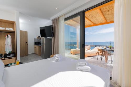 a bedroom with a bed and a view of the ocean at Soho SeaFront Suites in Hersonissos
