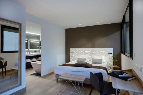 1 dormitorio con 1 cama grande y baño en Hôtel In Situ, en Béziers