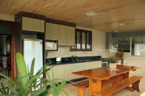 a kitchen with a wooden table and a refrigerator at Casa de temporada - Tatuhouse in José Boiteux