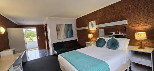 a bedroom with a large bed and a brick wall at Whalers Rest Motor Inn in Portland