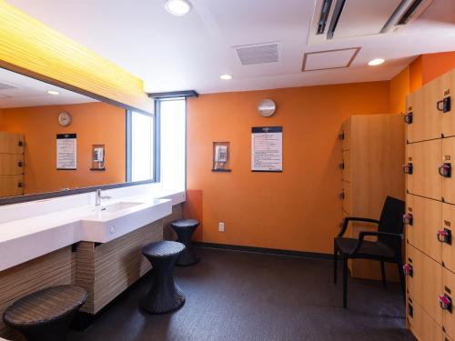 a bathroom with orange walls and a sink and a window at APA Hotel Nagoya Sakae in Nagoya