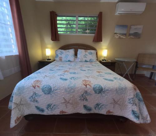 a bedroom with a bed with a floral bedspread at Isla Hermosa Guesthouse in Vieques