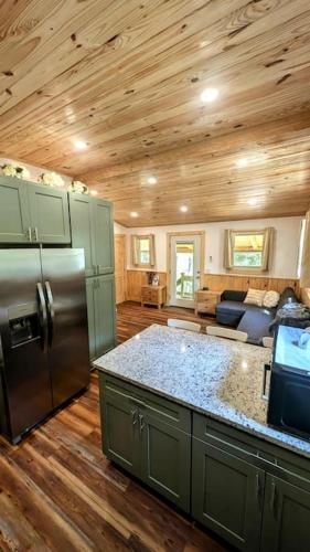 a kitchen with a stainless steel refrigerator and wooden ceilings at River Retreat Cabin - Living Water Farm in Cleveland