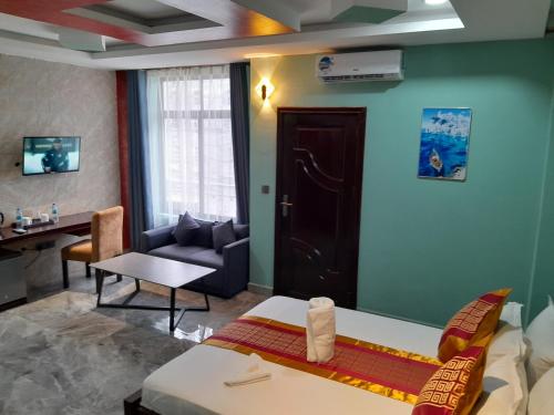 a room with a bed and a couch and a table at Mazola Diamond Hotel in Dar es Salaam