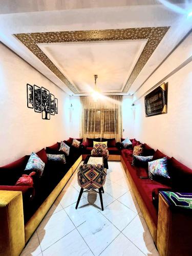 a living room with red couches and a table at Apprt Ennakhil 3 in El Jadida