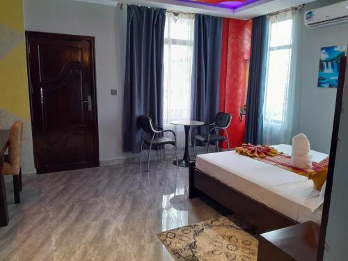 a bedroom with a bed and a table and chairs at Mazola Diamond Hotel in Dar es Salaam