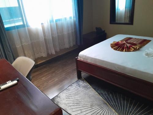 a bedroom with a bed and a desk and a table at Mazola Diamond Hotel in Dar es Salaam