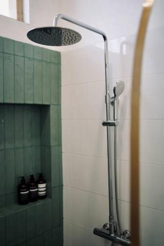 a shower in a bathroom with green and white tiles at Villa Cabana Amed in Amed
