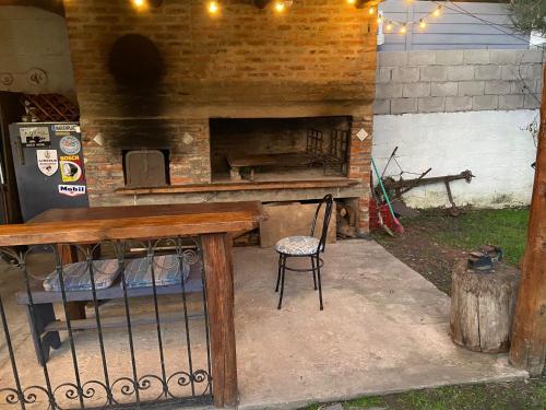 an outdoor fireplace with a wooden table and a chair at Cabaña con piscina in Atlántida