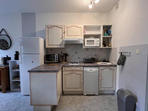La cuisine est équipée d'appareils électroménagers blancs et d'un réfrigérateur. dans l'établissement Appartement T2 à Cauterets - 6 pers, parking, citycab gratuit - FR-1-234-325, à Cauterets