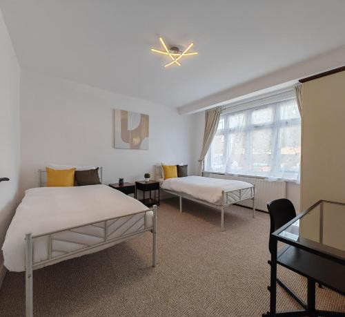 a bedroom with two beds and a window at 4 Bedroom 2 Bathroom House - Free parking in Ponders End