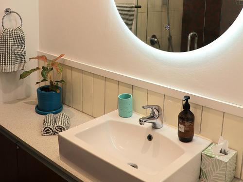 a bathroom sink with a bottle of soap and a mirror at Pavilions Marina Apartment 102 - Wynyard Quarter Viaduct Harbour in Auckland