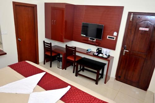 a hotel room with a table and chairs and a television at Swami Prasad Paradise hotel in Golitattu